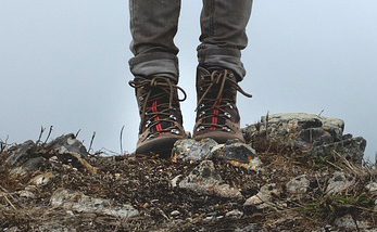 A pair of hiking boots on rocky ground.